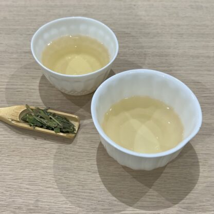 Infusion de thé Long Jing dans tasses blanches